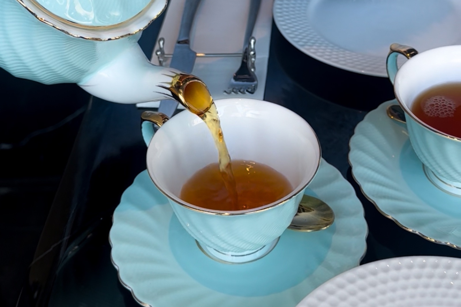 水色のティーカップに紅茶を注ぐ様子