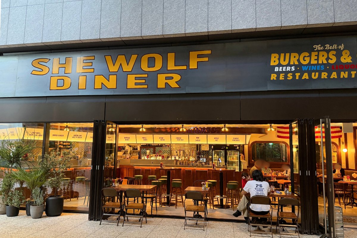 SHE WOLF DINER TOKYO の外観。黄色いSHE WOLF DINERの看板と全面開口の入口